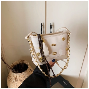 Detail of cream white patent leather tote bag with gold bone charm and cat paw studs