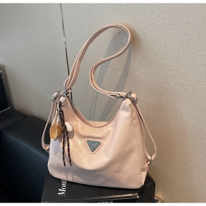 Detail of pink leather tote bag with metal triangle logo and baseball charm