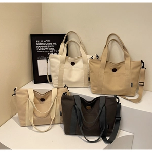 Multiple colors of large canvas tote bags on display stands with adjustable straps