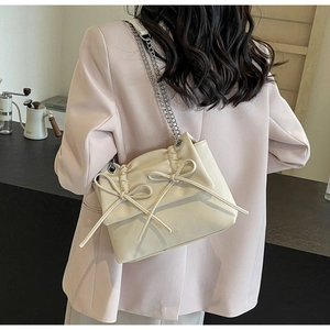 Detailed back view of a beige pleated crossbody bag with delicate bow accents
