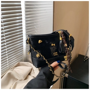 Detail of black tote bag with gold dog charm ornaments and silk scarf on strap