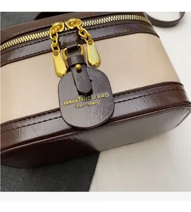 Detailaufnahme der zweifarbigen Retro-Eimertasche mit Lederstruktur und Goldkette