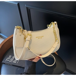 Detail of cream woven hobo bag showing gold logo lettering and metallic chain strap