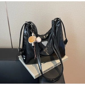 Detail of glossy black tote bag with silver triangle plaque and baseball charms