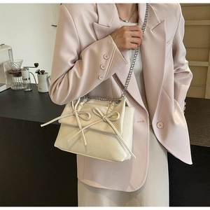 Detail of off-white crossbody bag featuring double bows and silver chain strap