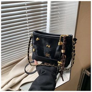 Detail of black leather tote bag with gold punk charms, skull studs and chain strap