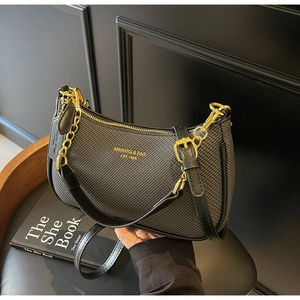 Detail of black textured hobo bag with gold logo, leather trim, and metal chain