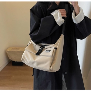 Detail van de beige nylon schoudertas met voorflapzak en zwarte verstelbare riem