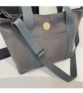 Detail of adjustable long shoulder strap with metal buckle on grey canvas tote bag