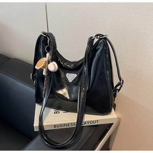 Detail of glossy black tote bag with triangle logo and baseball charm accessory