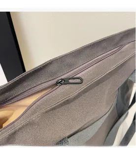 Close-up of smooth metal zipper and gray canvas texture on casual tote bag