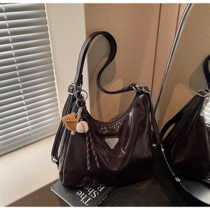 Detailed macro of dark brown glossy leather tote bag with silver triangle plaque and charm