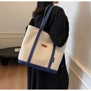 Detailed side view of high-capacity canvas tote bag with contrast strap on a model