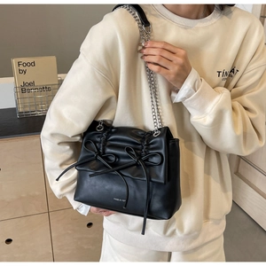 Detail view of black pleated crossbody bag with bow accents and silver chain strap