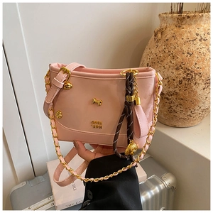 Detail of light pink crossbody bag featuring gold bone hardware and woven rope charm