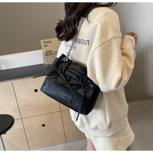 Close-up of black crossbody bag with double bow decoration and silver chain strap