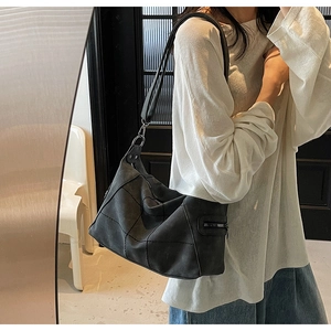 Detail of black suede shoulder bag featuring decorative side metal zipper and matte texture