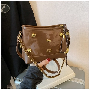Detailed shot of brown vintage tote with gold dog charms and tassels on black background