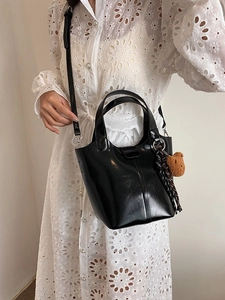 Elegante bolso de cubo negro con colgante de oso y vestido de encaje blanco