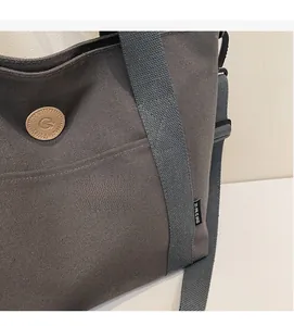 Detail of dark grey canvas tote bag showing material texture and logo branding emblem