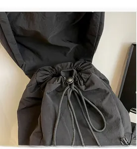 Détail du sac à dos de voyage en nylon noir montrant le cordon et le fermoir à ressort