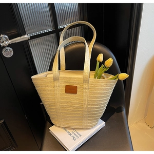 Detailed texture of woven straw tote bag featuring a brown leather fashion tag detail