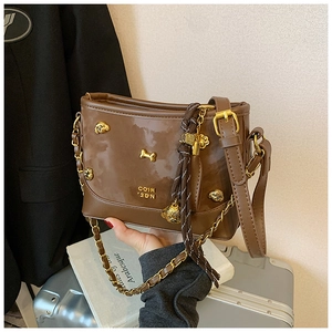 Detail of vintage brown patent leather tote with gold dog head and bone metal ornaments