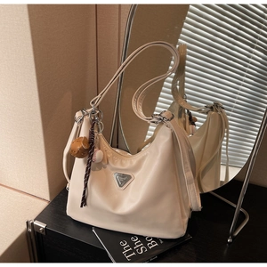 Detail of off-white nylon tote bag with silver triangle metal logo and baseball charm
