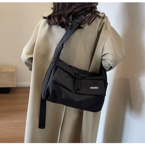 Detail van de zwarte nylon crossbodytas met merklabel en een brede schouderriem
