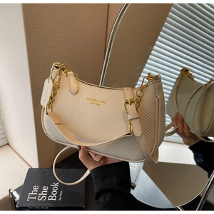 Detailed macro view of beige woven texture and gold lettering on shoulder bag