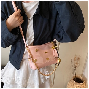 Detail of pink patent leather tote bag with gold bone charms and floral silk scarf accessory