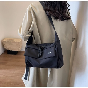 Detail van zwarte nylon schoudertas met verstelbare brede riem en voorvak met een klep