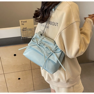 Detail of light blue pleated bag with bow accents and silver metal chain strap