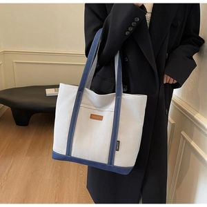 Detail of blue and white canvas tote bag with leather logo tag and sturdy handles