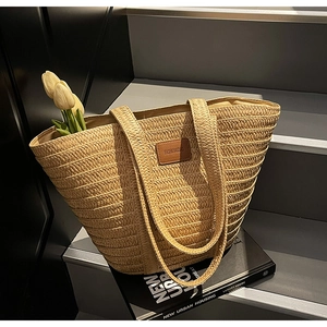 Macro detail of hand-woven straw tote featuring a brown leather patch and chic texture