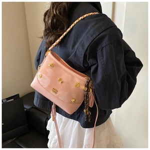 Pink patent leather tote with gold skull studs and braided tassel on a shoulder strap