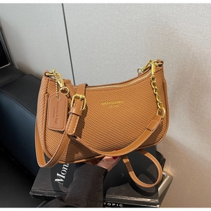 Detail of brown woven shoulder bag featuring gold chain and adjustable leather strap