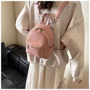 Detail view of pink mini backpack with twill texture worn by a model in casual setting
