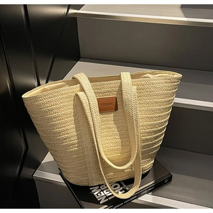 Close-up of woven straw tote bag with brown leather patch and horizontal texture