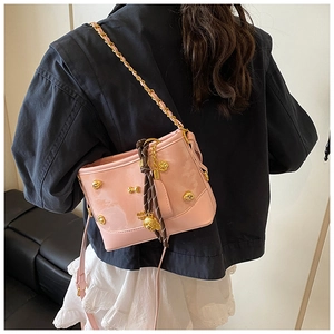 Detail of pink patent leather tote with gold animal studs and chain strap on a model