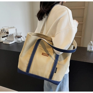 Close-up of durable canvas tote bag with leather logo and sturdy navy handles