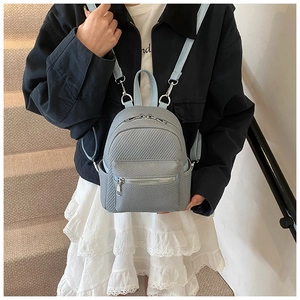 Close-up of light blue mini backpack showing woven texture and silver zipper details