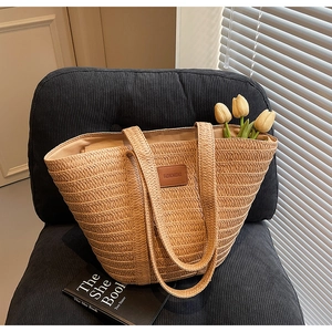 Close-up of natural straw tote bag with woven texture and brown leather brand patch