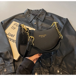 Close-up of black woven shoulder bag with gold chain and MIKAXIQI & BAG logo