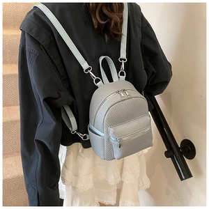 Rear view of a model wearing a light blue textured mini backpack with silver zippers