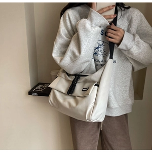 Detail van de gebroken witte crossbodytas met zwarte ritsen en een stijlvolle flap