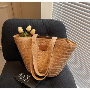 Detail of light brown straw tote bag with leather logo patch and yellow tulips inside