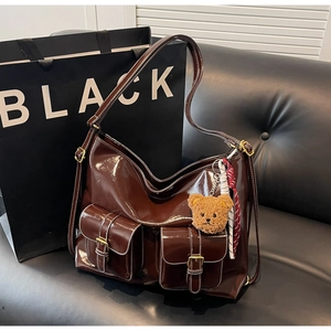 Détail du sac hobo marron foncé brillant avec coutures contrastées et charm ourson