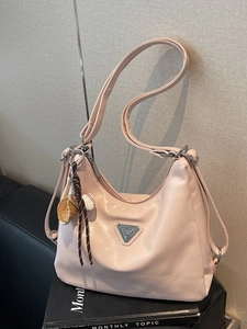 Pink crescent shoulder bag with silver plaque and sports charm on a book