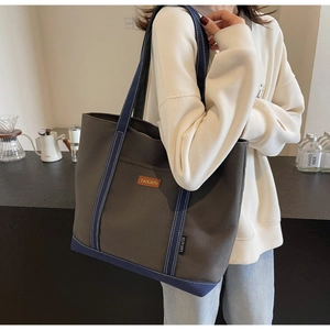 Detail of grey canvas tote bag with blue straps and contrast stitching on the shoulder bag